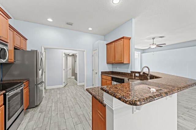 4672 SW Wade Dr, Port Saint Lucie, FL 34953 - kitchen with stainless steel appliances, a sink, a kitchen breakfast bar, light wood-type flooring, and a ceiling fan
