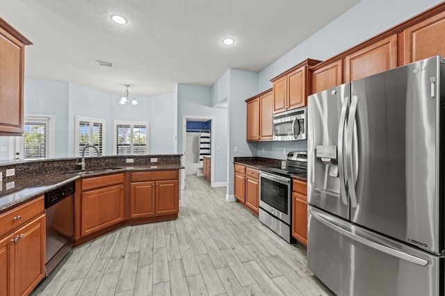 4672 SW Wade Dr, Port Saint Lucie, FL 34953 - kitchen with appliances with stainless steel finishes, brown cabinetry, a sink, a textured ceiling, and a chandelier