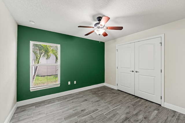 4672 SW Wade Dr, Port Saint Lucie, FL 34953 - unfurnished bedroom with a textured ceiling, wood finished floors, a closet, baseboards, and a ceiling fan