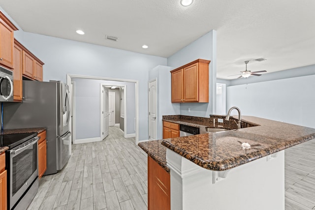 4672 SW Wade Dr, Port Saint Lucie, FL 34953 - kitchen featuring appliances with stainless steel finishes, a sink, a breakfast bar area, light wood finished floors, and a ceiling fan