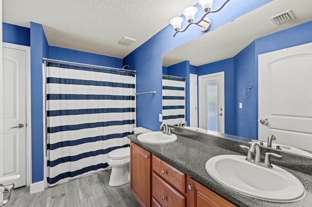 4672 SW Wade Dr, Port Saint Lucie, FL 34953 - full bath with toilet, double vanity, wood finished floors, a shower with curtain, and a textured ceiling