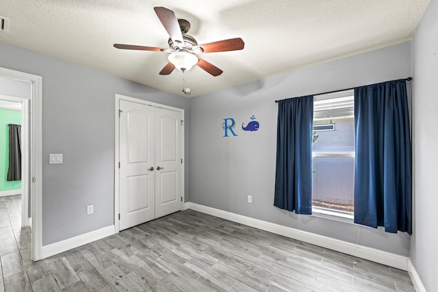 4672 SW Wade Dr, Port Saint Lucie, FL 34953 - unfurnished bedroom with wood finished floors, baseboards, a closet, a ceiling fan, and a textured ceiling