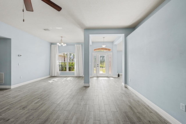4672 SW Wade Dr, Port Saint Lucie, FL 34953 - unfurnished living room featuring wood finished floors, baseboards, a ceiling fan, a textured ceiling, and a chandelier