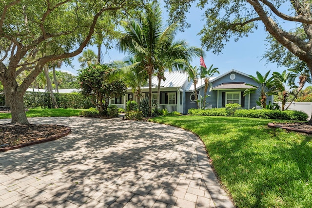 10 Copaire Rd, Sewalls Point, FL 34996 - ranch-style house featuring a front lawn, a porch, metal roof, and curved driveway