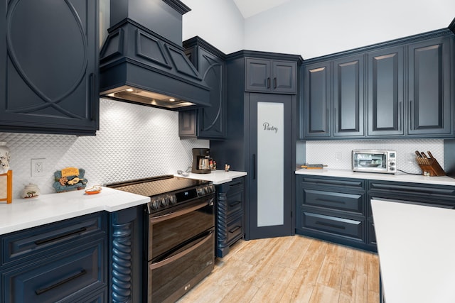 10 Copaire Rd, Sewalls Point, FL 34996 - kitchen featuring range with two ovens, premium range hood, light countertops, light wood-style floors, and backsplash