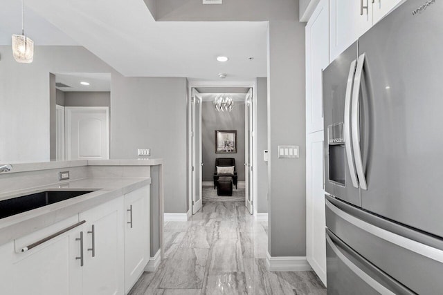 701 S Olive Ave Unit 923, West Palm Beach, FL 33401 - kitchen featuring stainless steel fridge with ice dispenser, light marble finish flooring, baseboards, a sink, and white cabinets