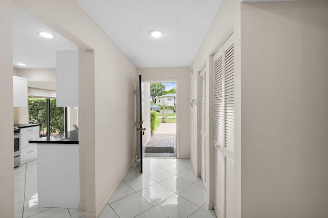 12 Westgate Ln Unit C, Boynton Beach, FL 33436 - hallway featuring plenty of natural light, recessed lighting, baseboards, light tile patterned flooring, and a textured ceiling