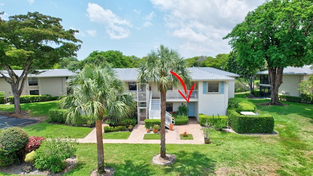 12 Westgate Ln Unit C, Boynton Beach, FL 33436 - view of front facade featuring stairway, a front yard, a tile roof, and stucco siding