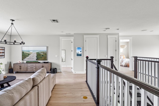 12277 Waterstone Cir, Palm Beach Gardens, FL 33412 - hall with a chandelier, an upstairs landing, light wood-type flooring, and baseboards