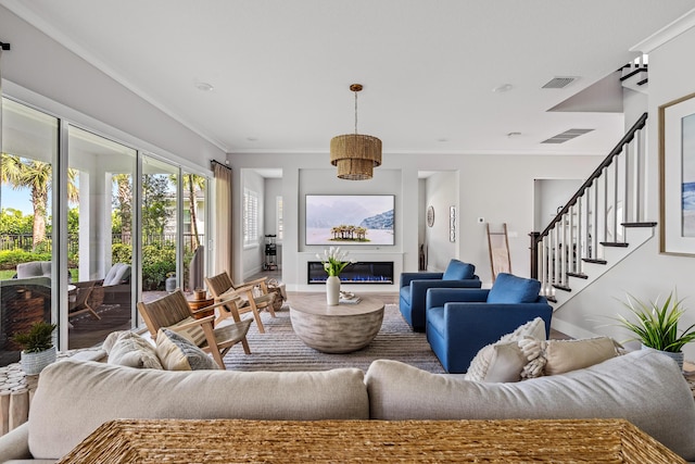 12277 Waterstone Cir, Palm Beach Gardens, FL 33412 - living area featuring crown molding, a glass covered fireplace, wood finished floors, stairway, and baseboards