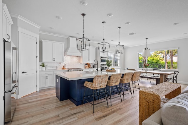 12277 Waterstone Cir, Palm Beach Gardens, FL 33412 - kitchen with custom range hood, light countertops, crown molding, appliances with stainless steel finishes, and light wood-type flooring