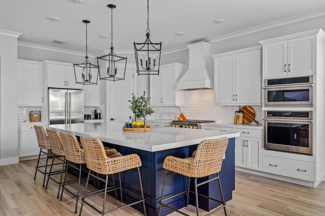 12277 Waterstone Cir, Palm Beach Gardens, FL 33412 - kitchen with appliances with stainless steel finishes, custom range hood, crown molding, a large island, and a chandelier