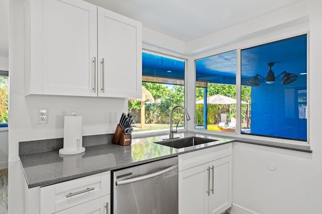 5031 Van Buren Rd, Delray Beach, FL 33484 - kitchen with stainless steel dishwasher, a sink, white cabinets, and dark stone countertops