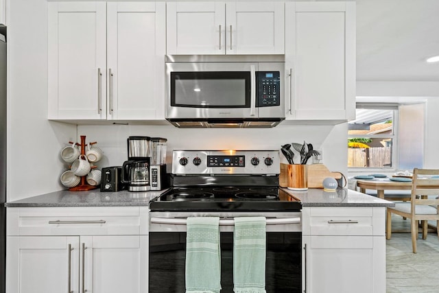 5031 Van Buren Rd, Delray Beach, FL 33484 - kitchen featuring appliances with stainless steel finishes, white cabinetry, and dark stone countertops