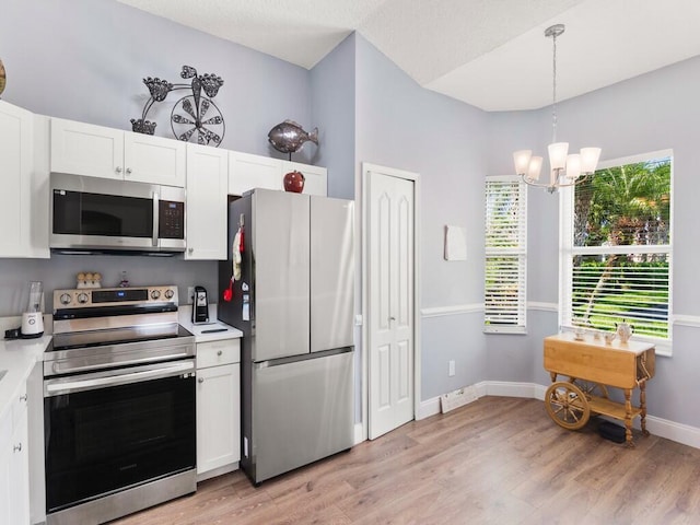 470 NW Gibraltar Ct, Port Saint Lucie, FL 34986 - kitchen with stainless steel appliances, a chandelier, white cabinetry, and light wood-style floors