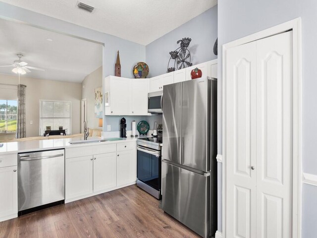 470 NW Gibraltar Ct, Port Saint Lucie, FL 34986 - kitchen featuring stainless steel appliances, a sink, a ceiling fan, wood finished floors, and white cabinets