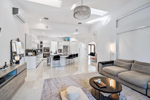 125 Pembroke Dr, Palm Beach Gardens, FL 33418 - living area featuring a skylight, light marble finish floors, ornamental molding, arched walkways, and a wall mounted air conditioner