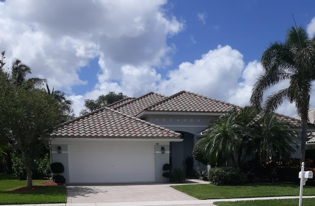 6687 Jog Palm Dr, Boynton Beach, FL 33437 - mediterranean / spanish-style house with a tiled roof, decorative driveway, a garage, stucco siding, and a front lawn