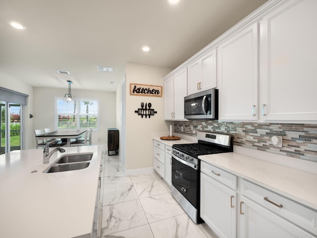 10621 SW Morning Glory Dr, Port Saint Lucie, FL 34987 - kitchen with stainless steel appliances, a sink, light marble finish flooring, white cabinets, and plenty of natural light