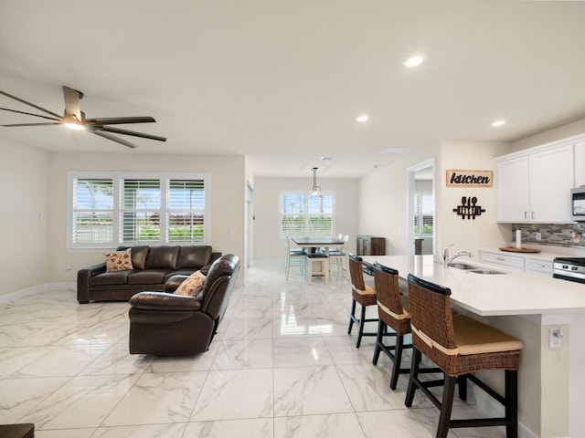 10621 SW Morning Glory Dr, Port Saint Lucie, FL 34987 - living room with healthy amount of natural light, light marble finish flooring, baseboards, recessed lighting, and a ceiling fan