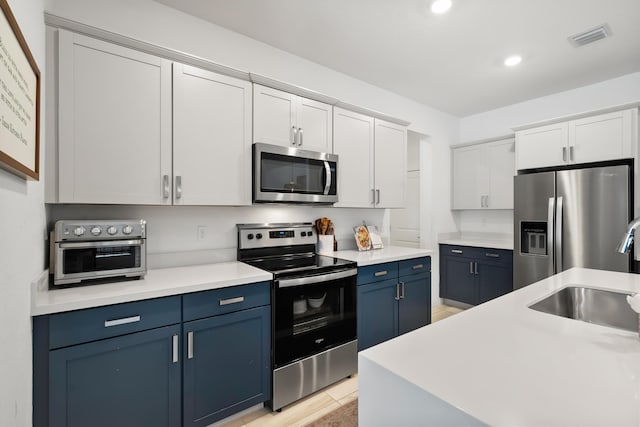 7102 Rockwood Rd, Jupiter, FL 33458 - kitchen with stainless steel appliances, blue cabinetry, a sink, white cabinetry, and recessed lighting