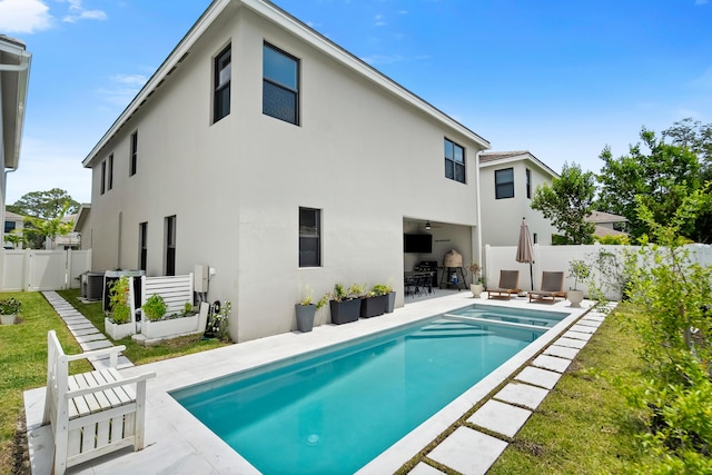 7102 Rockwood Rd, Jupiter, FL 33458 - back of property with stucco siding, a patio, ceiling fan, a pool with connected hot tub, and central AC