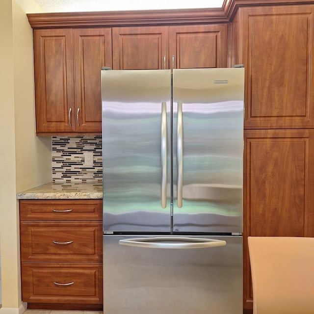 10231 N Circle Lake Dr Unit 101, Boynton Beach, FL 33437 - kitchen featuring freestanding refrigerator, brown cabinetry, decorative backsplash, and light stone countertops
