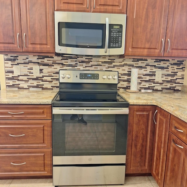 10231 N Circle Lake Dr Unit 101, Boynton Beach, FL 33437 - kitchen featuring stainless steel appliances, decorative backsplash, light stone countertops, and brown cabinets