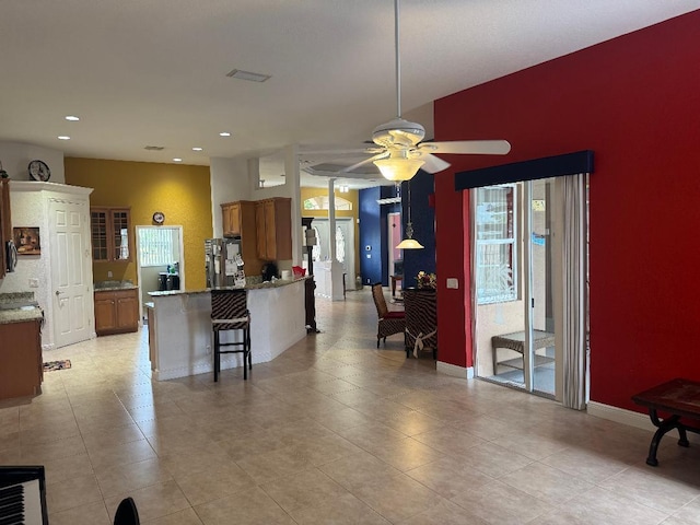 5760 NW Cleburn Dr, Port Saint Lucie, FL 34986 - kitchen featuring brown cabinetry, a ceiling fan, a peninsula, a breakfast bar area, and recessed lighting