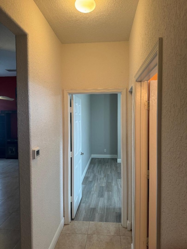 5760 NW Cleburn Dr, Port Saint Lucie, FL 34986 - corridor featuring a textured wall, tile patterned floors, a textured ceiling, and baseboards