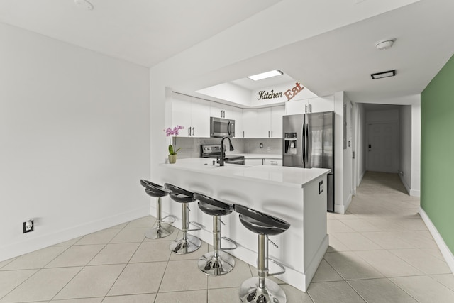 9500 SW 3rd St SW Unit 130, Boca Raton, FL 33428 - kitchen with appliances with stainless steel finishes, light countertops, a peninsula, baseboards, and a breakfast bar area