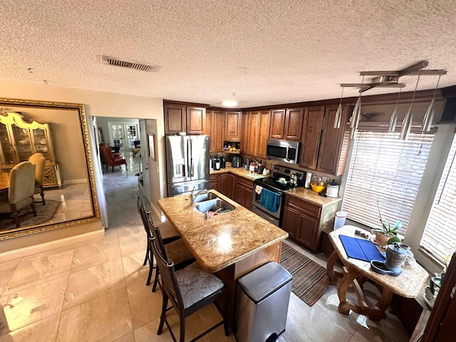 5473 E Berry Blossom Way E, West Palm Beach, FL 33415 - kitchen with appliances with stainless steel finishes, a sink, an island with sink, a kitchen breakfast bar, and hanging light fixtures