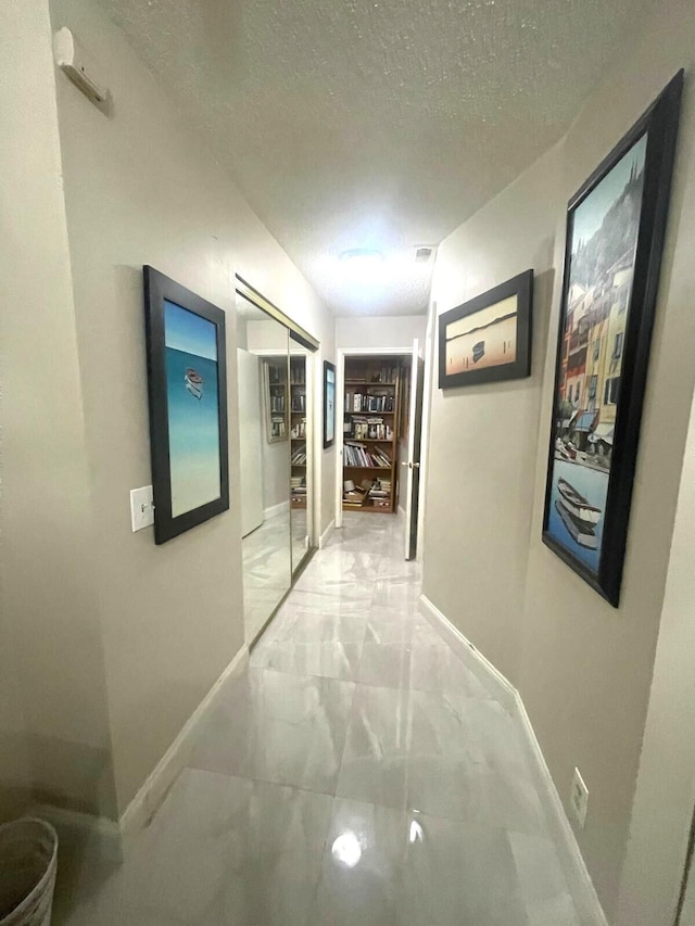 5473 E Berry Blossom Way E, West Palm Beach, FL 33415 - hall with light marble finish flooring, a textured ceiling, and baseboards