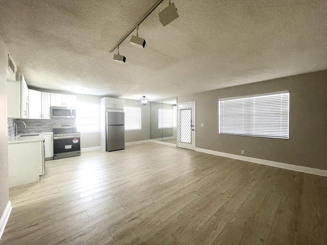 222 Piedmont E, Delray Beach, FL 33484 - unfurnished living room featuring a textured ceiling, light wood-style flooring, and baseboards
