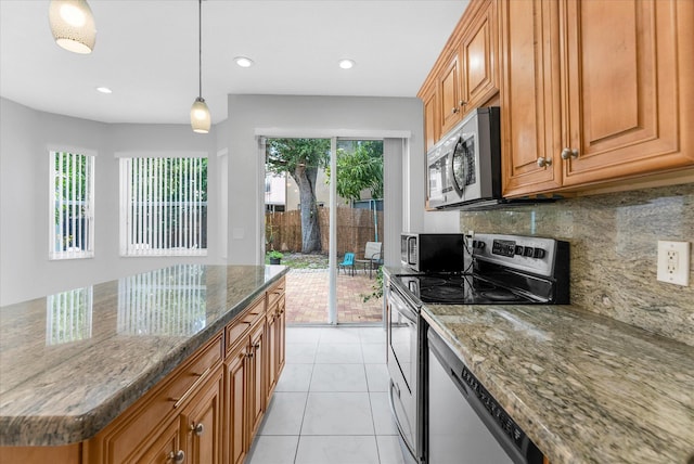 5814 Eagle Cay Ln, Coconut Creek, FL 33073 - kitchen with stainless steel appliances, dark stone counters, backsplash, brown cabinetry, and recessed lighting
