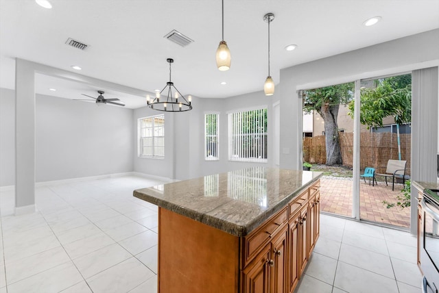 5814 Eagle Cay Ln, Coconut Creek, FL 33073 - kitchen featuring brown cabinetry, light tile patterned floors, dark stone counters, a kitchen island, and hanging light fixtures
