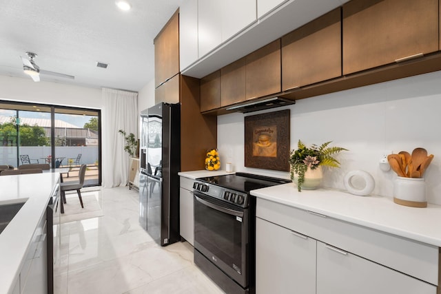 1783 SW Erie St, Port Saint Lucie, FL 34953 - kitchen with range with electric cooktop, black fridge with ice dispenser, under cabinet range hood, light countertops, and light marble finish flooring