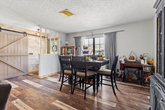 5706 Eagle Dr, Fort Pierce, FL 34950 - dining area featuring wood finished floors, baseboards, wooden walls, a textured ceiling, and a barn door