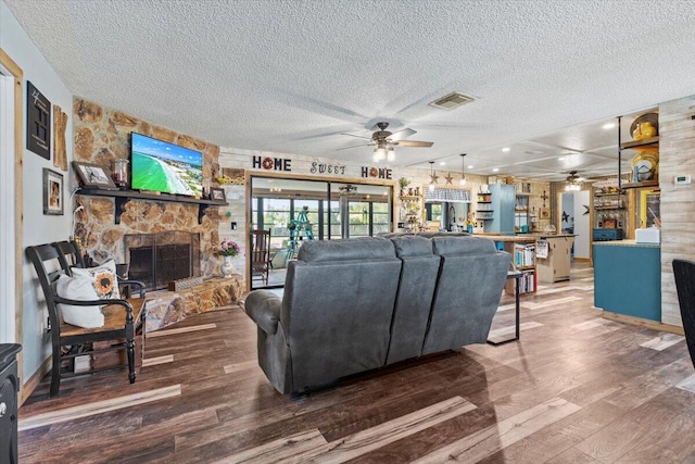 5706 Eagle Dr, Fort Pierce, FL 34950 - living room featuring a ceiling fan, a textured ceiling, a fireplace, and wood finished floors