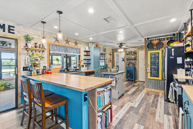 5706 Eagle Dr, Fort Pierce, FL 34950 - kitchen featuring stainless steel appliances, wooden counters, wood finished floors, a ceiling fan, and wood walls