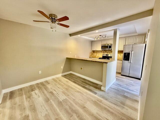 3611 SW Sunset Trace Cir, Palm City, FL 34990 - kitchen with stainless steel appliances, a peninsula, light wood-type flooring, baseboards, and decorative backsplash