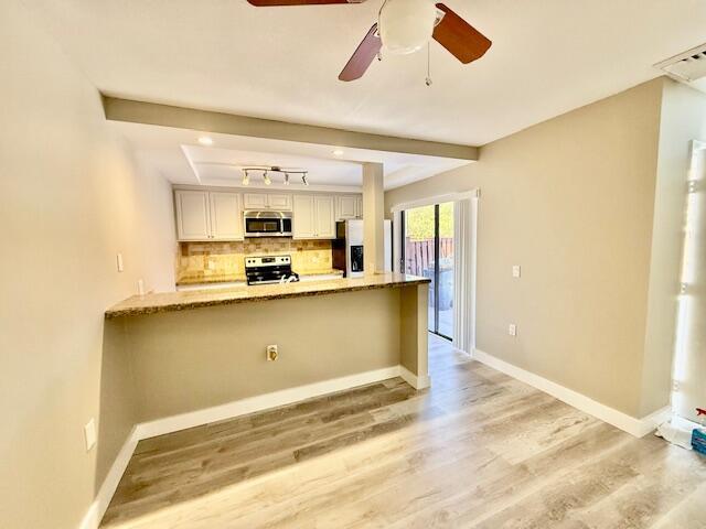 3611 SW Sunset Trace Cir, Palm City, FL 34990 - kitchen with stainless steel appliances, light wood-type flooring, light stone countertops, backsplash, and a peninsula