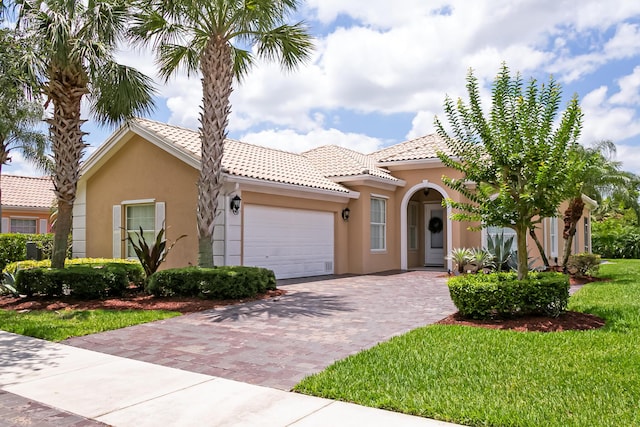10581 SW Stratton Dr, Port Saint Lucie, FL 34987 - mediterranean / spanish house with a garage, stucco siding, decorative driveway, a tiled roof, and a front yard