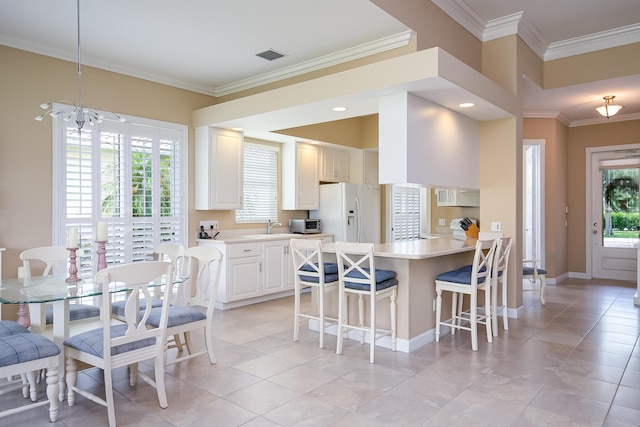 10581 SW Stratton Dr, Port Saint Lucie, FL 34987 - kitchen featuring white appliances, a breakfast bar area, light tile patterned flooring, light countertops, and a peninsula