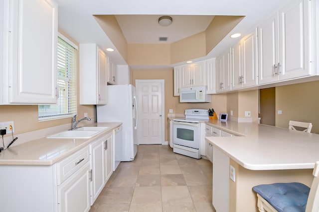 10581 SW Stratton Dr, Port Saint Lucie, FL 34987 - kitchen with white appliances, a sink, a breakfast bar, a peninsula, and white cabinets