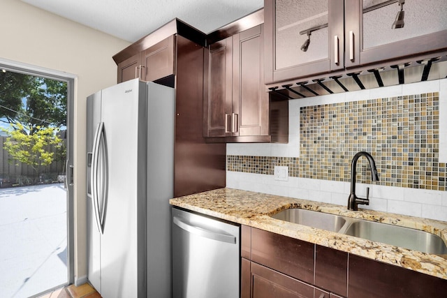 202 2nd Ct, Palm Beach Gardens, FL 33410 - kitchen with stainless steel dishwasher, refrigerator with ice dispenser, a sink, tasteful backsplash, and light stone countertops