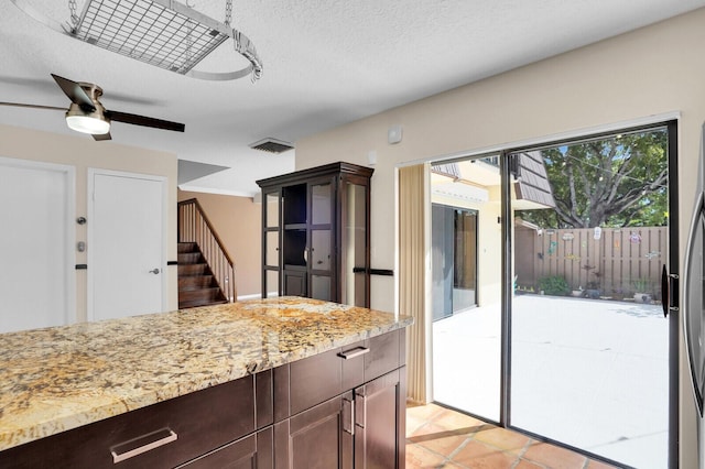 202 2nd Ct, Palm Beach Gardens, FL 33410 - kitchen featuring light stone countertops, ceiling fan, and dark brown cabinetry