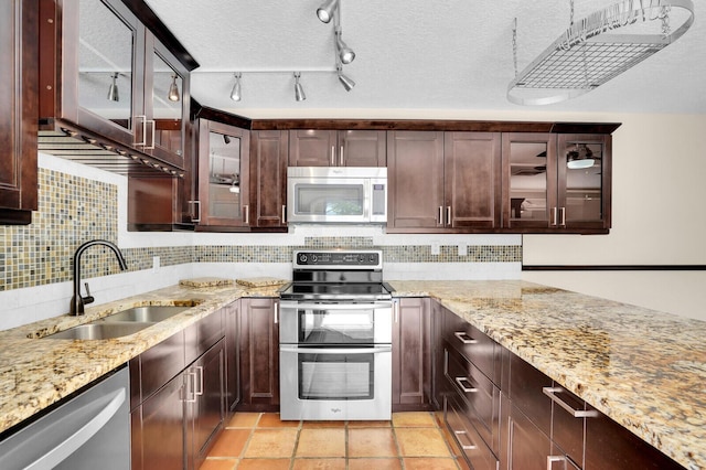 202 2nd Ct, Palm Beach Gardens, FL 33410 - kitchen featuring stainless steel appliances, a sink, decorative backsplash, light stone counters, and dark brown cabinets
