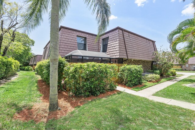 7678 Courtyard Run W, Boca Raton, FL 33433 - view of front of home featuring mansard roof, a front yard, and brick siding