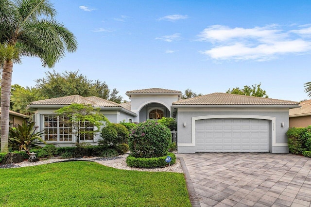 7208 Corning Cir, Boynton Beach, FL 33437 - mediterranean / spanish-style home featuring a garage, decorative driveway, stucco siding, a front lawn, and a tiled roof